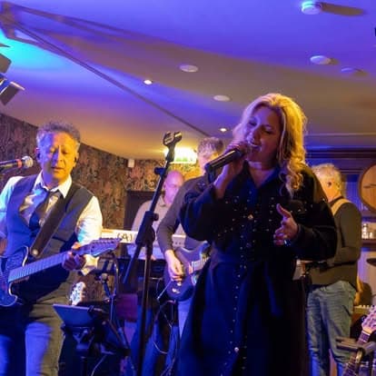 De zangeres en gitarist van DaVinci spelen in een sfeervol café